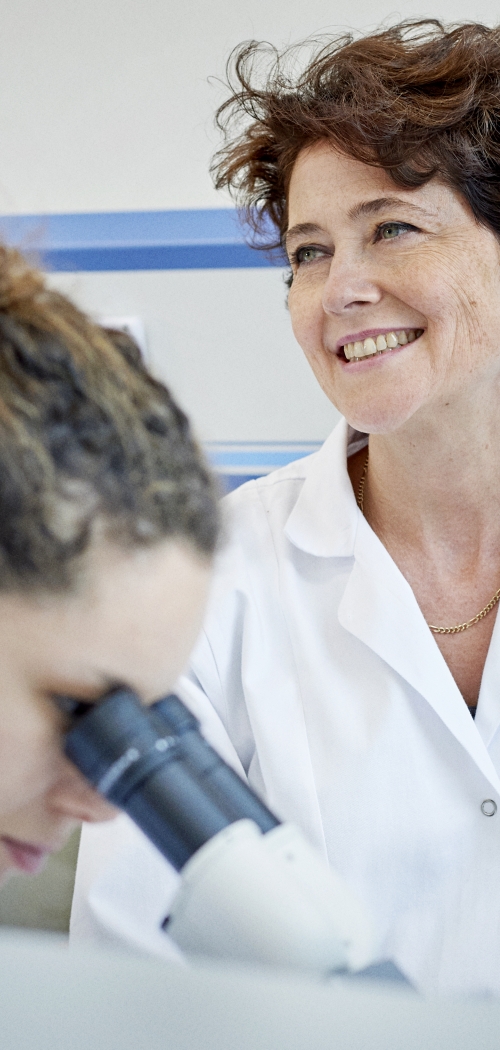 Two women scientists in a laboratory. They use a microscope.